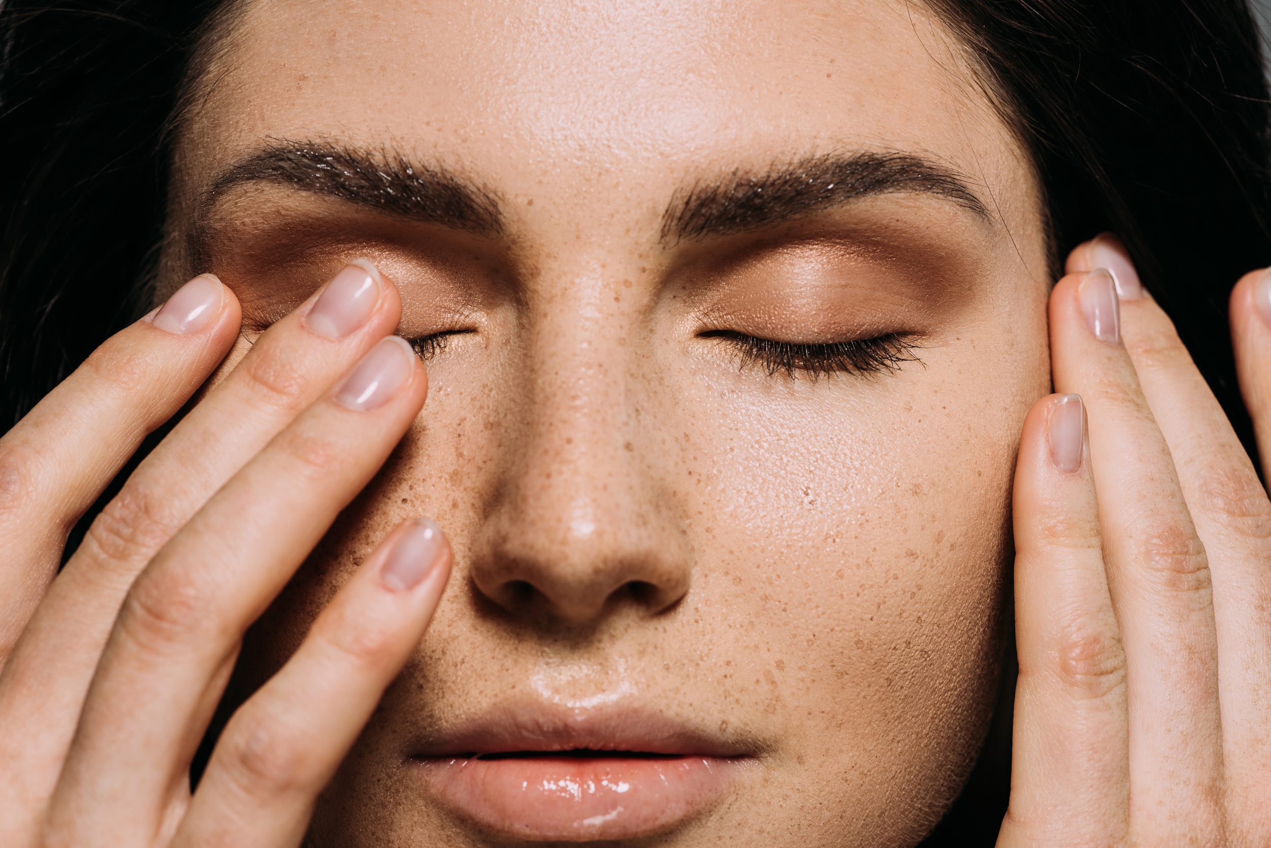 Picture of a beautiful woman with eyes closed and one hand half covering an eye