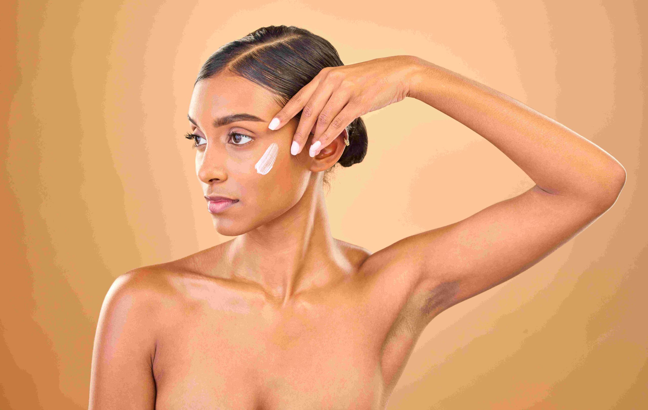 Olive Skin woman showing off nails, putting on white cream on face.