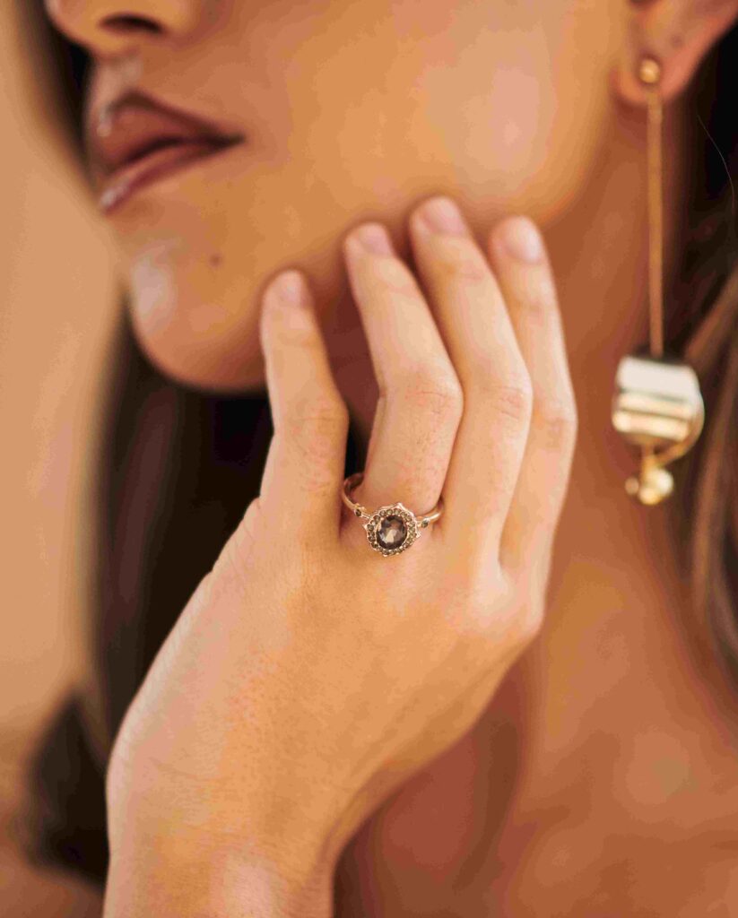 A woman hand wearing a vintage-style ring while touching her face