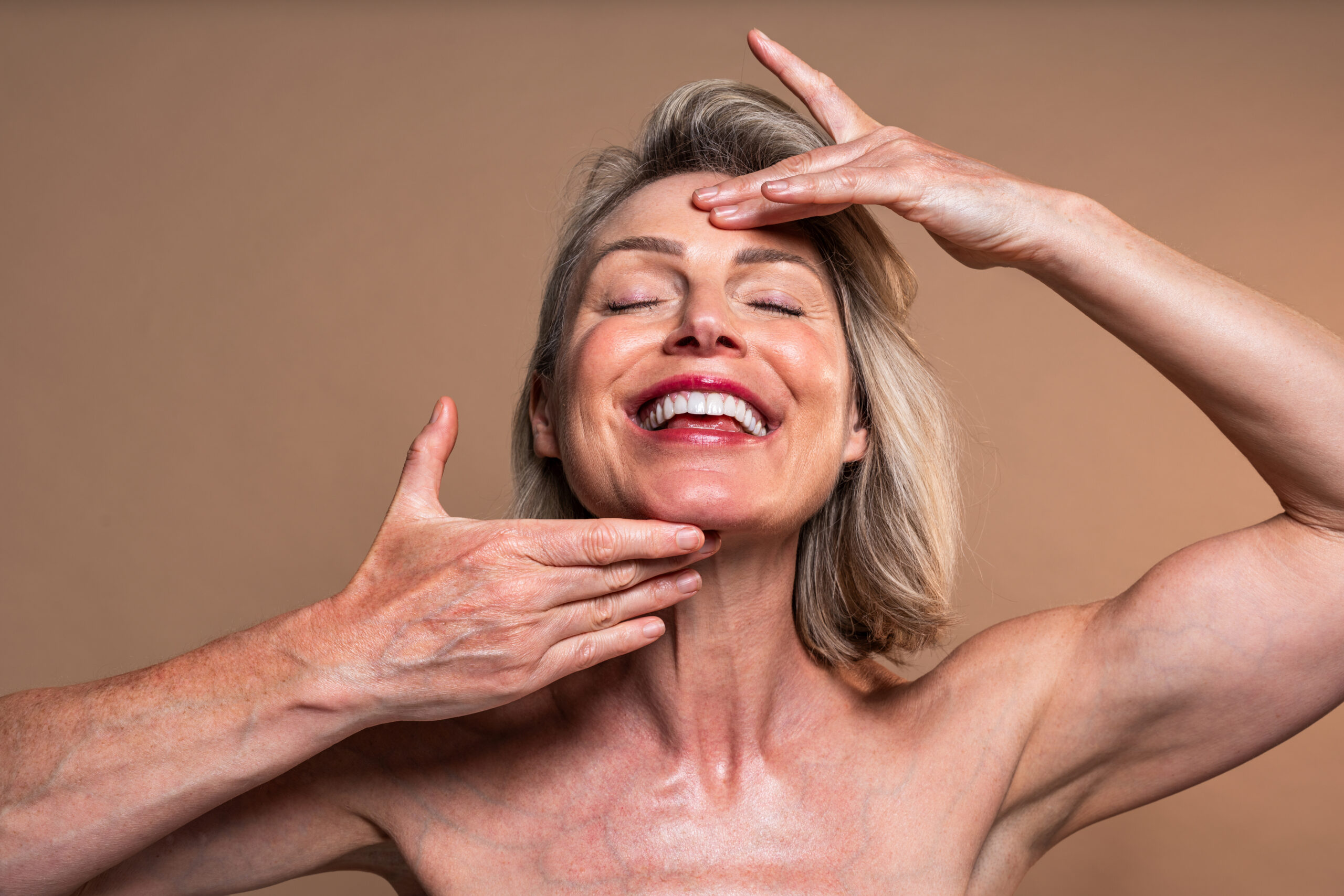 Beauty portrait of beautiful mature woman, concepts about cosmetics, skincare and wellness. Mature woman with closed eyes gently touching face